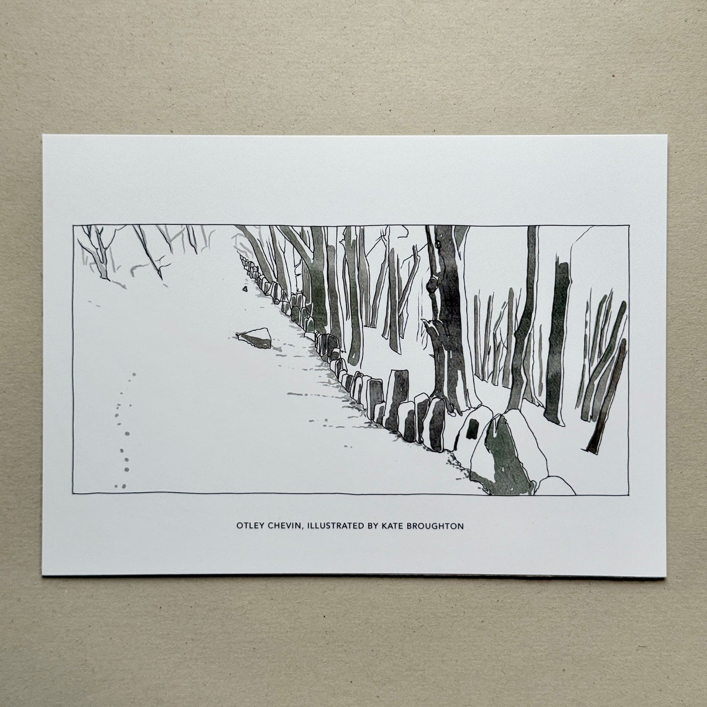 printed illustration of a snowy landscape with a path and trees. Labelled: Otley Chevin, Illustrated by Kate Broughton